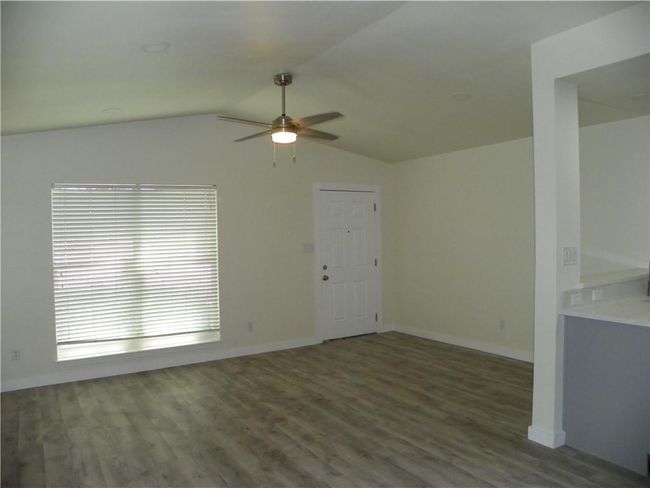 Unfurnished living room featuring a ceiling fan, wood finished floors, and lofted ceiling | Image 8