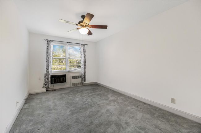 Spare room featuring carpet flooring, a ceiling fan, and radiator heating unit | Image 15