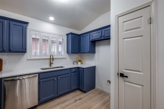 Kitchen with a sink, light countertops, stainless steel dishwasher, blue cabinets, and lofted ceiling | Image 11