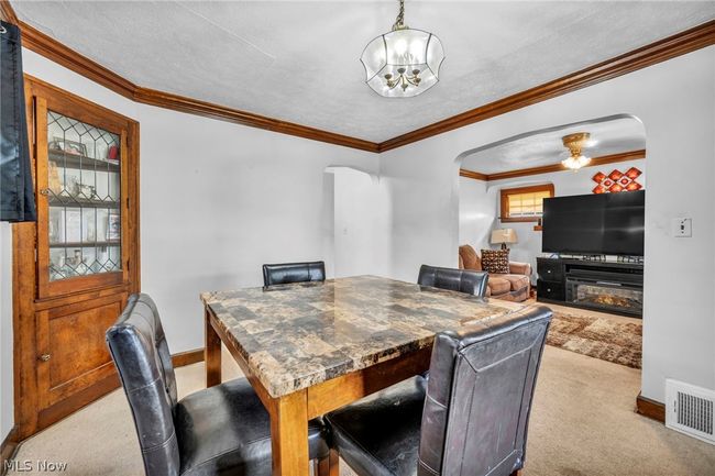 Carpeted dining room featuring ornamental molding and ceiling fan with notable chandelier | Image 11