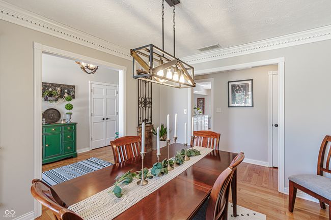 dining area with light wood-type flooring, baseboards, visible vents, a notable chandelier, and ornamental molding | Image 4