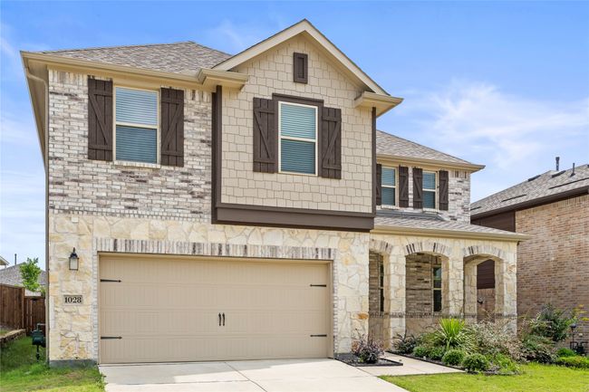 View of front of home with a garage, covered porch, stone siding, and roof with shingles | Image 40