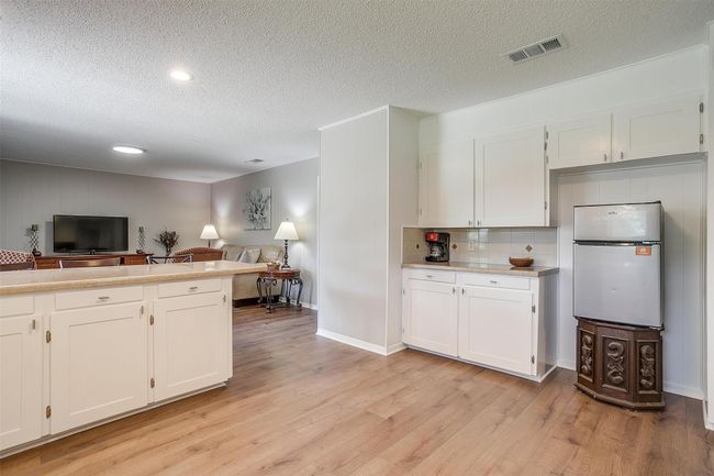 Kitchen featuring freestanding refrigerator, open floor plan, a textured ceiling, light wood-type flooring, and white cabinetry | Image 18