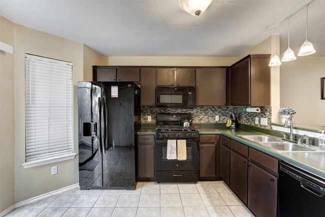 Kitchen featuring black appliances, a sink, decorative backsplash, and light tile patterned flooring | Image 16