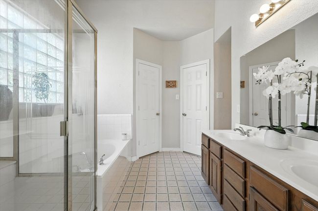 Bathroom with double vanity, a bath, a stall shower, and tile patterned flooring | Image 21