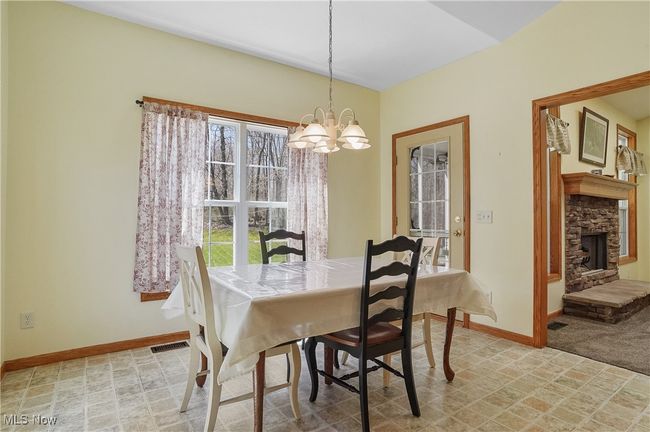 Dining room featuring baseboards, an inviting chandelier, visible vents, and a fireplace | Image 24