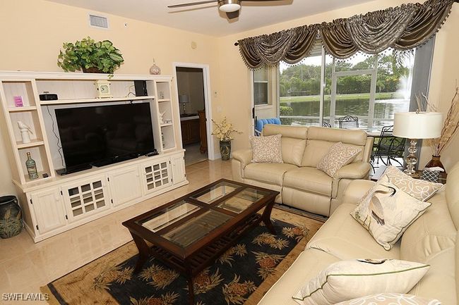 Living room featuring ceiling fan, a water view, and light tile floors | Image 5