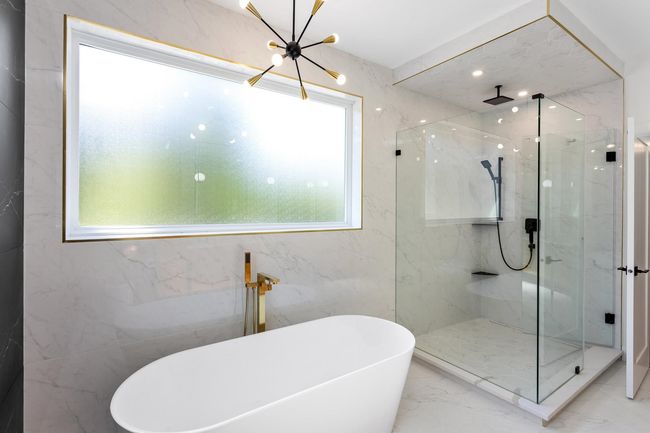 Full bath featuring an inviting chandelier, marble finish floor, a marble finish shower, and a freestanding bath | Image 26
