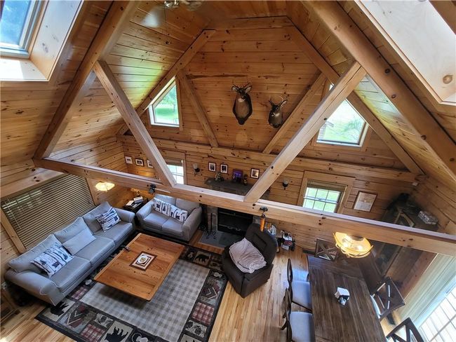 Unfurnished living room with wood-type flooring, lofted ceiling with beams, wooden walls, and wood ceiling | Image 6