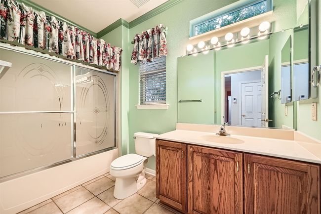 Bathroom featuring vanity, toilet, tile patterned floors, shower / bath combination with glass door, and ornamental molding | Image 20