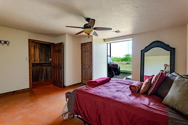 Bedroom with finished concrete floors, ceiling fan, baseboards, access to exterior, and visible vents | Image 25