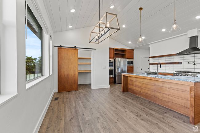 Kitchen featuring open shelves, appliances with stainless steel finishes, baseboards, recessed lighting, and a barn door | Image 11