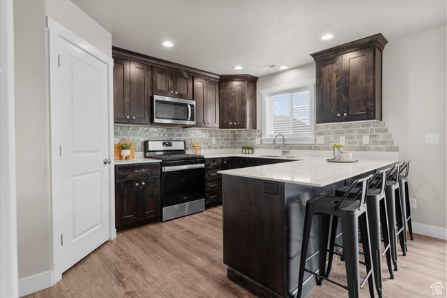 Kitchen featuring stainless steel appliances, a sink, baseboards, light wood-style floors, and recessed lighting | Image 16