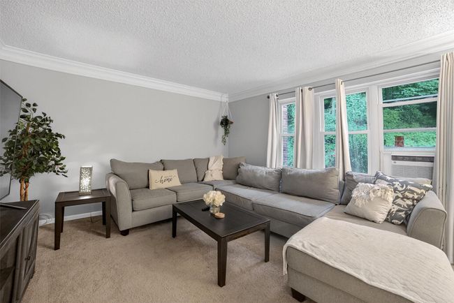 Living room featuring ornamental molding, a textured ceiling, light colored carpet, and cooling unit | Image 7