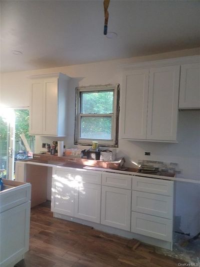 Kitchen featuring a wealth of natural light, white cabinets, and dark hardwood / wood-style flooring | Image 2