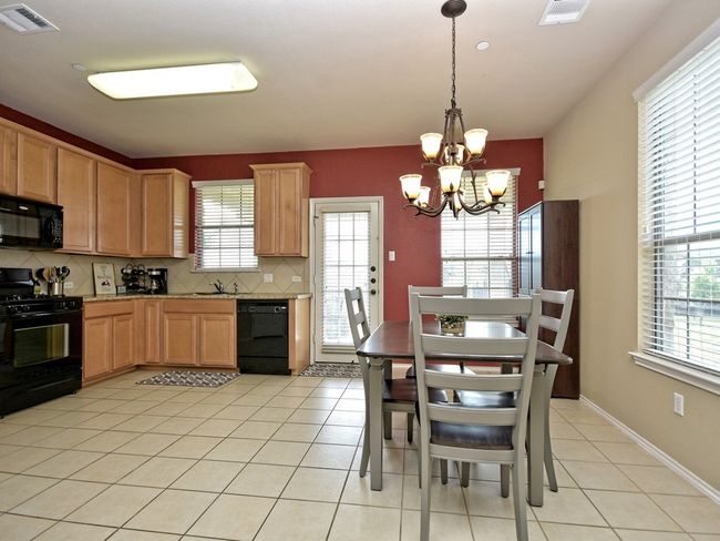 Kitchen with an inviting chandelier, plenty of natural light, and black appliances | Image 9