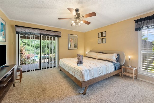 Bedroom with a textured ceiling, ceiling fan, crown molding, and carpet | Image 12