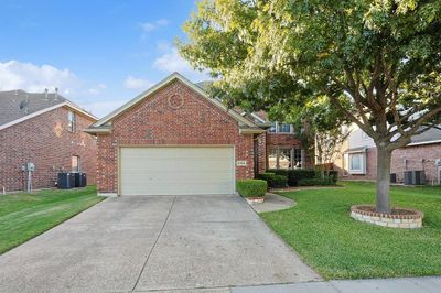 Front facade featuring cooling unit, a front lawn, and a garage | Image 1