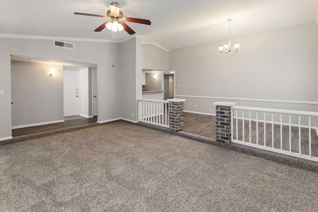 Empty room with a ceiling fan, carpet floors, ornamental molding, and a chandelier | Image 14