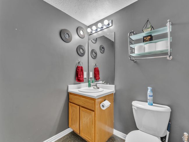 Bathroom featuring vanity, toilet, a textured ceiling, and baseboards | Image 22