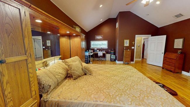 Owner's suite with wood finished floors, an office area, baseboards, high vaulted ceiling, and recessed lighting | Image 13