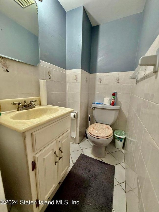 Bathroom featuring tile patterned flooring, vanity, tile walls, and toilet | Image 4