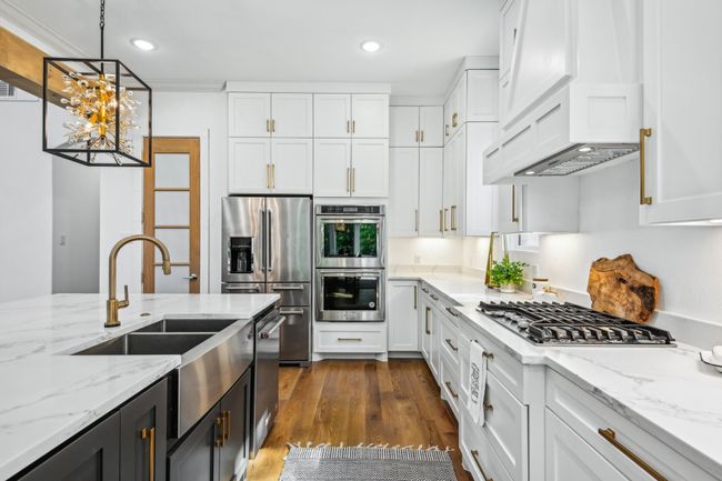 Kitchen featuring white cabinets, stainless steel appliances, dark cabinets, custom range hood, and recessed lighting | Image 12