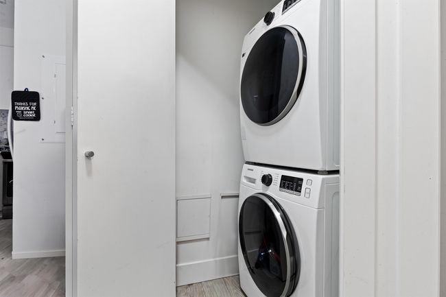 Laundry room with stacked washer and clothes dryer and light wood-type flooring | Image 23