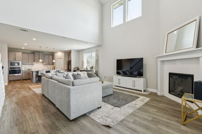 Living room featuring wood-style tile flooring, a high ceiling, a fireplace, and recessed lighting | Image 5