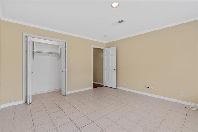 Unfurnished bedroom featuring a closet, light tile patterned floors, and ornamental molding | Image 26