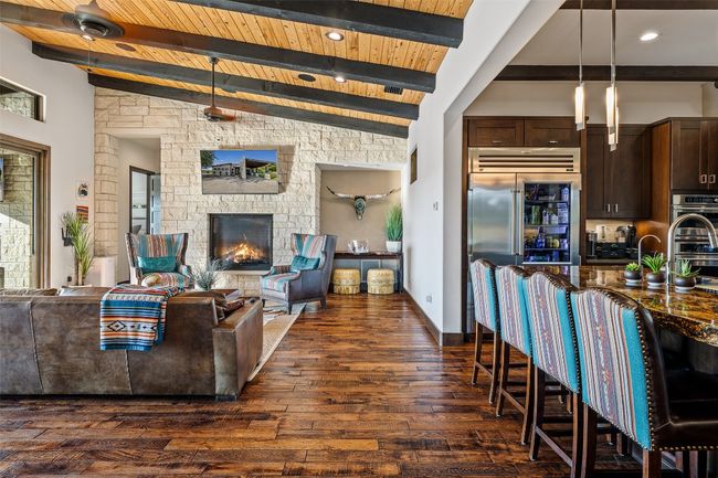 Living room with dark wood finished floors, a wooden ceiling with exposed beams, and a fireplace | Image 5