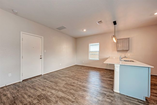 Kitchen with a sink, dark wood-type flooring, light countertops, hanging light fixtures, and recessed lighting | Image 10