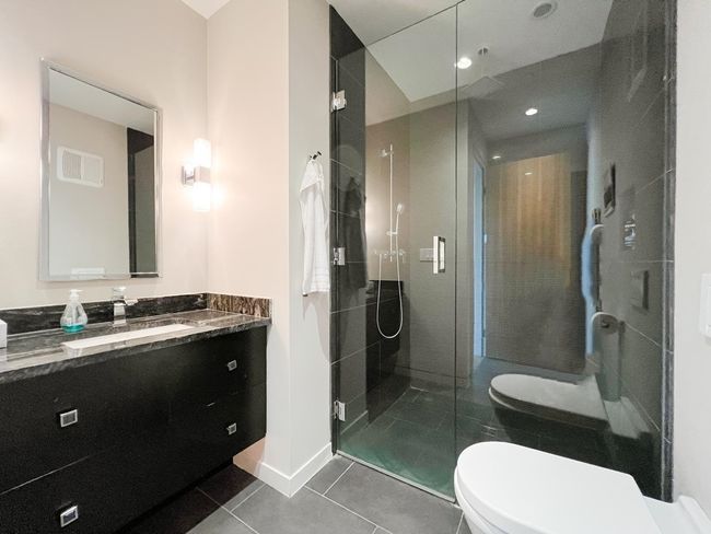 Bathroom featuring toilet, vanity, tile patterned floors, a shower stall, and baseboards | Image 27