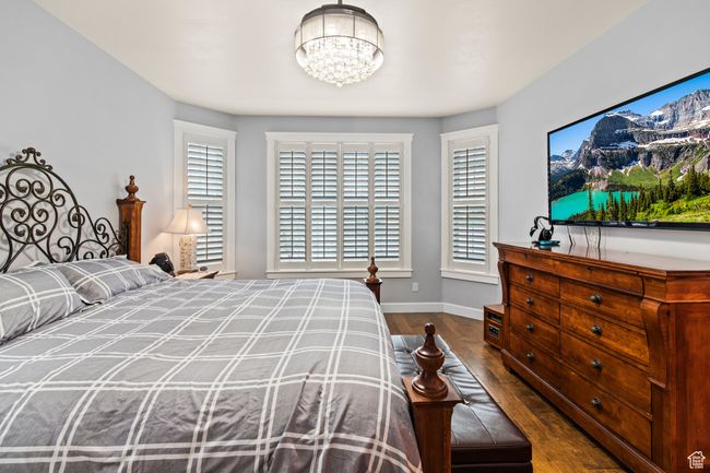 Bedroom with dark wood-type flooring and an inviting chandelier | Image 43