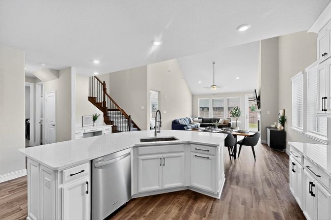 Kitchen featuring white cabinets, stainless steel dishwasher, open floor plan, lofted ceiling, and dark wood-style floors | Image 8