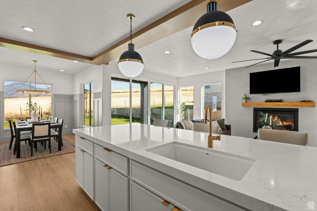 Kitchen featuring hanging light fixtures, recessed lighting, light wood-type flooring, light stone counters, and white cabinets | Image 18
