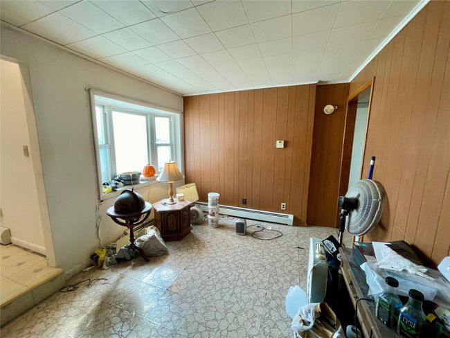 Living area with tile patterned floors, wooden walls, and a baseboard heating unit | Image 22