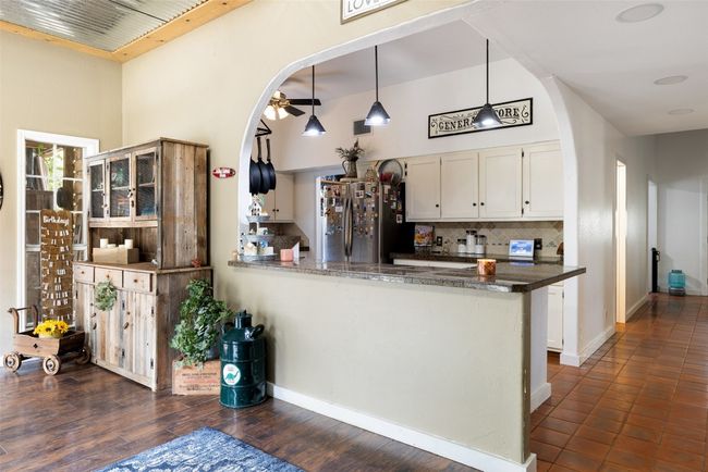 Kitchen featuring freestanding refrigerator, white cabinetry, backsplash, and arched walkways | Image 17