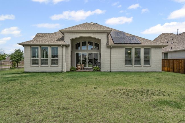 Back of house with roof mounted solar panels, brick siding, and a shingled roof | Image 33