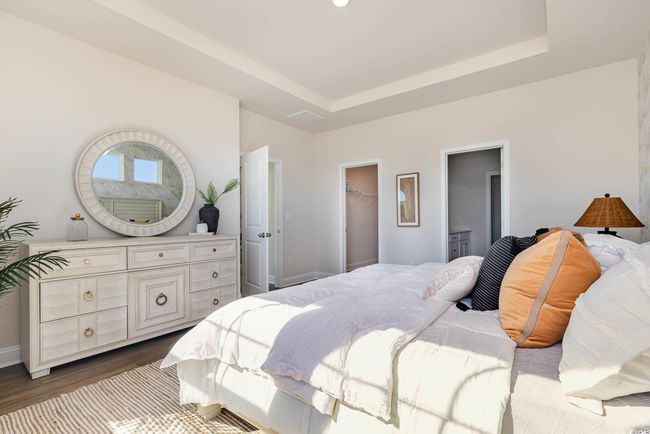 Bedroom featuring dark wood finished floors, a tray ceiling, baseboards, and a spacious closet | Image 22