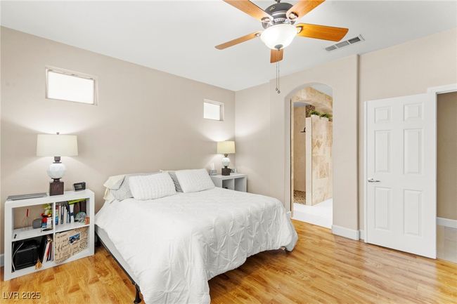 Bedroom featuring arched walkways, wood finished floors, baseboards, and a ceiling fan | Image 23