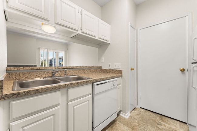 Kitchen featuring white cabinets, dishwasher, stone finish flooring, and a sink | Image 9