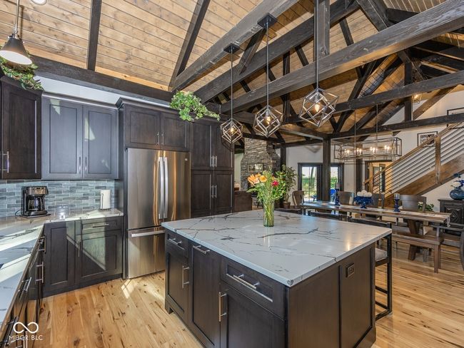 kitchen with freestanding refrigerator, wooden ceiling, a kitchen island, light wood-style floors, and backsplash | Image 16