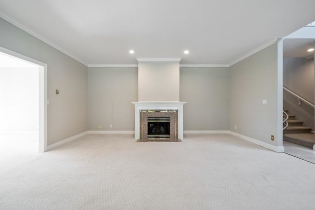 Unfurnished living room featuring crown molding, stairs, a high end fireplace, and baseboards | Image 7