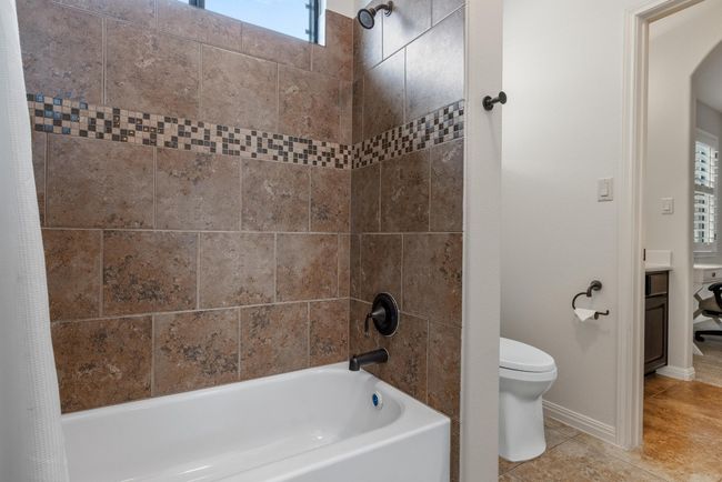 Full bathroom featuring toilet, tub / shower combination, tile patterned floors, and baseboards | Image 23