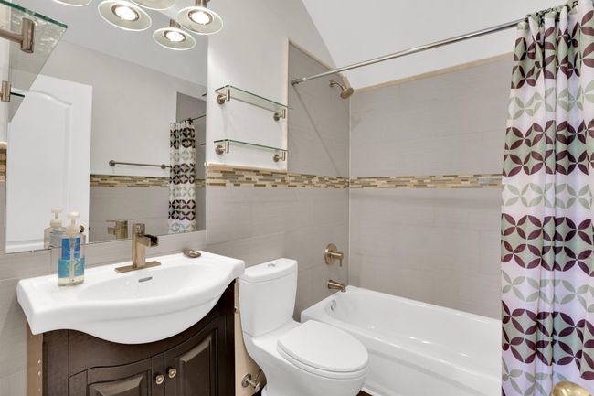 Bathroom featuring shower / tub combo, toilet, vanity, and tile walls | Image 23