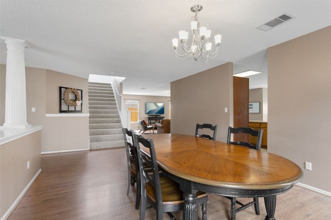 An elegant dining room featuring a chandelier, wood flooring, and a view of the second-story entry staircase. | Image 11