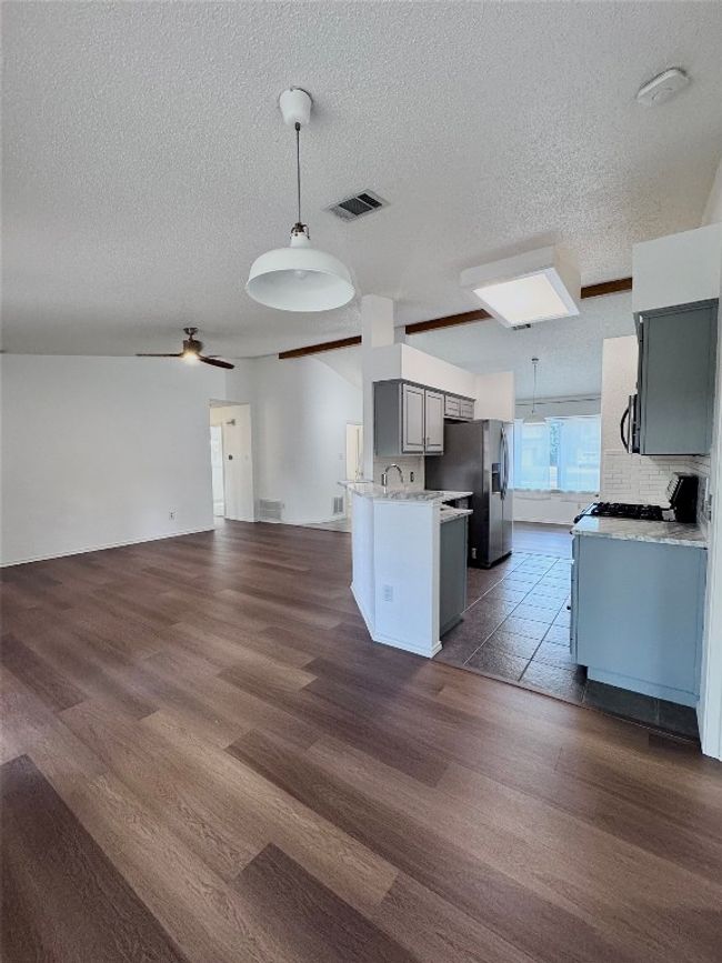 Kitchen featuring pendant lighting, open floor plan, gray cabinetry, a ceiling fan, and a textured ceiling | Image 8