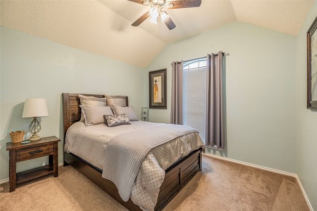 Bedroom with vaulted ceiling, light colored carpet, baseboards, and a ceiling fan | Image 33
