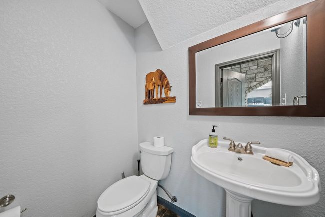Half bath with a textured wall, a sink, and toilet | Image 19
